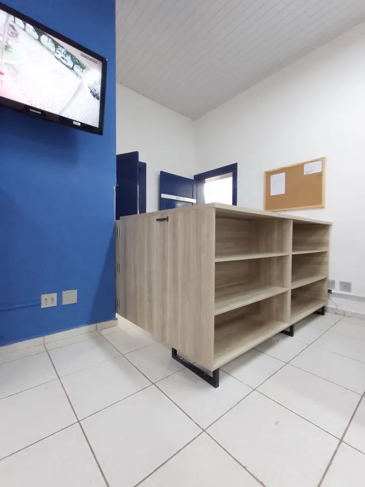 Estante planejada em MDF claro com porta e nichos abertos, parede azul ao fundo